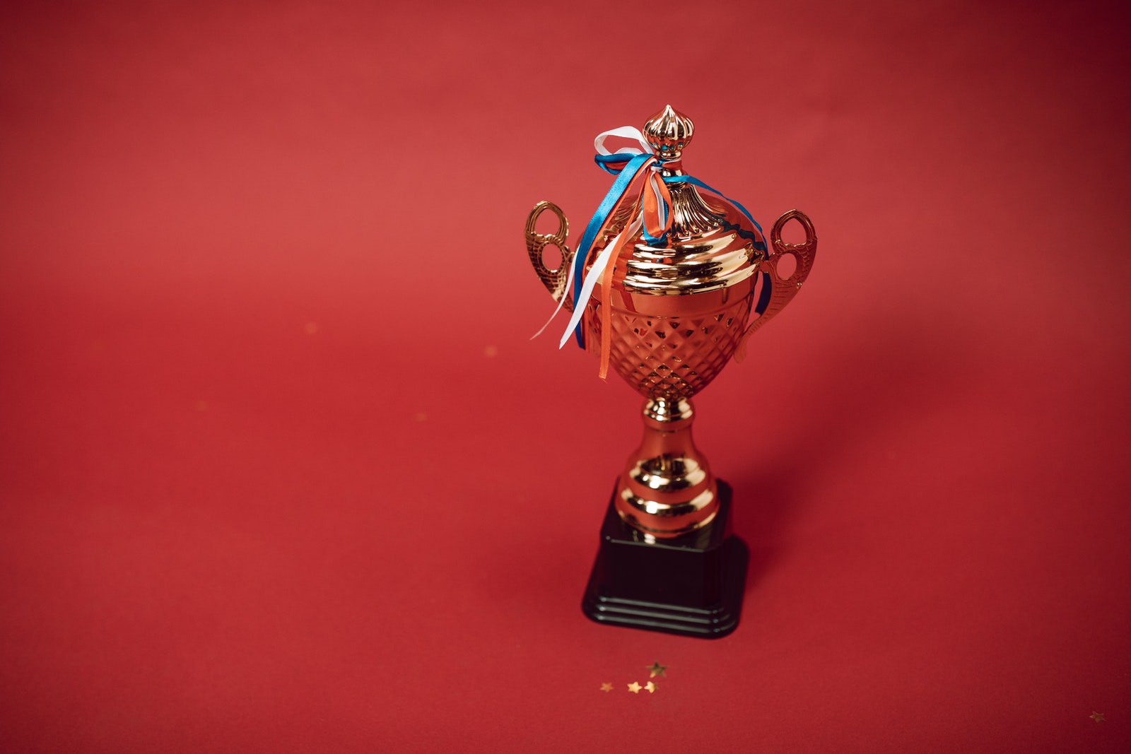 Photo by RODNAE Productions A Trophy with Tied Ribbons on Red Background