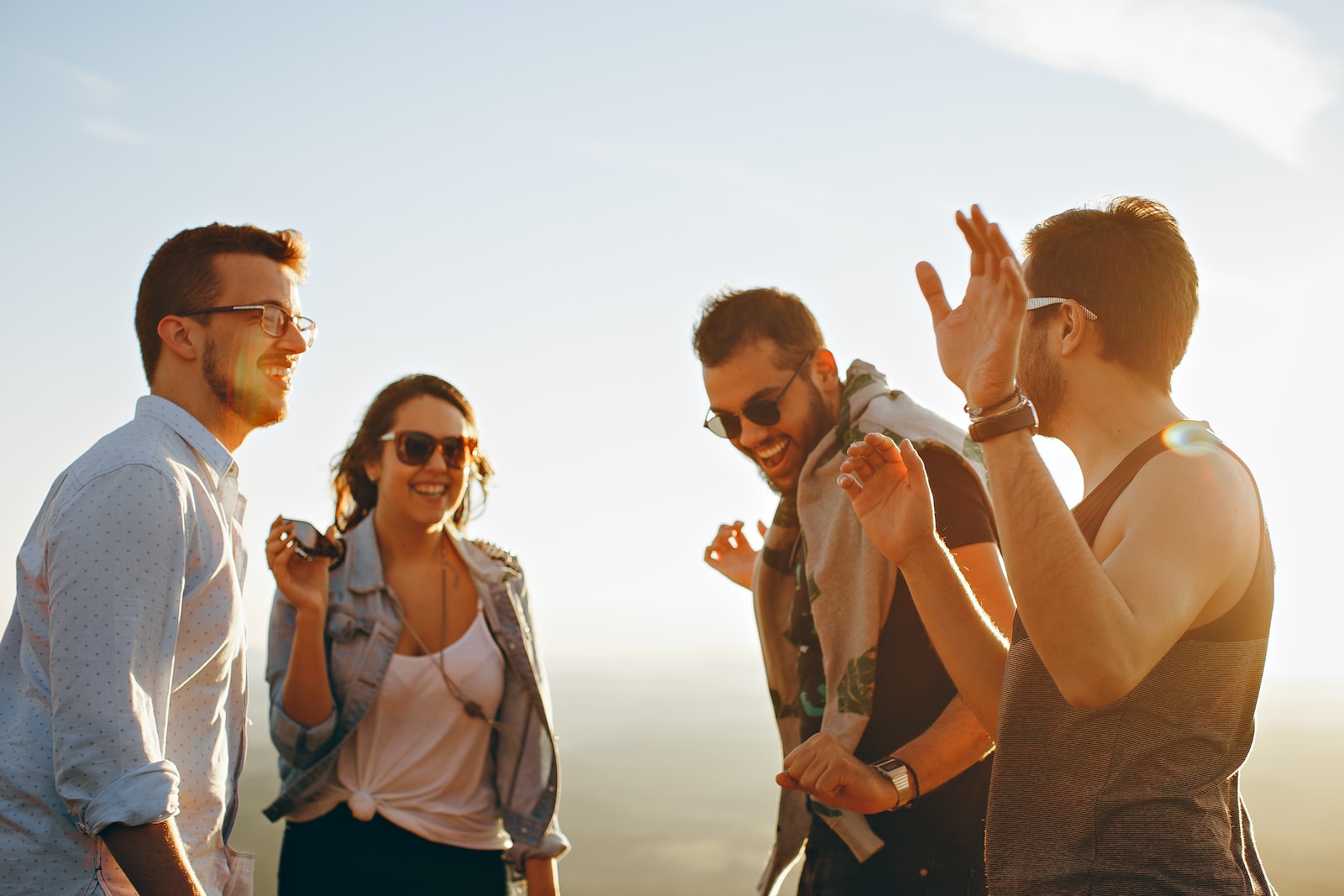 Photo by Helena Lopes three men and one woman laughing during daytime