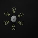 Conceptual photo of a brain surrounded by light bulb clips on black background.