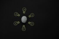 Conceptual photo of a brain surrounded by light bulb clips on black background.