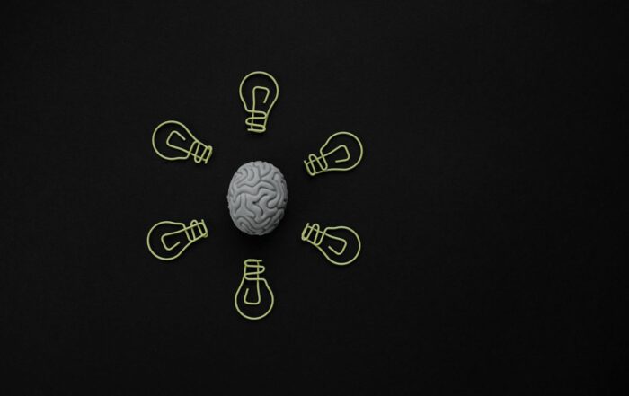 Conceptual photo of a brain surrounded by light bulb clips on black background.