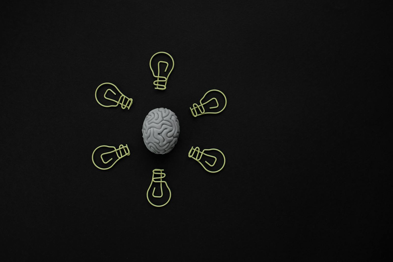 Conceptual photo of a brain surrounded by light bulb clips on black background.