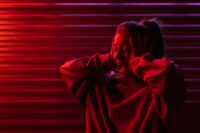 Woman with hands on head, expressing stress in neon red lighting.