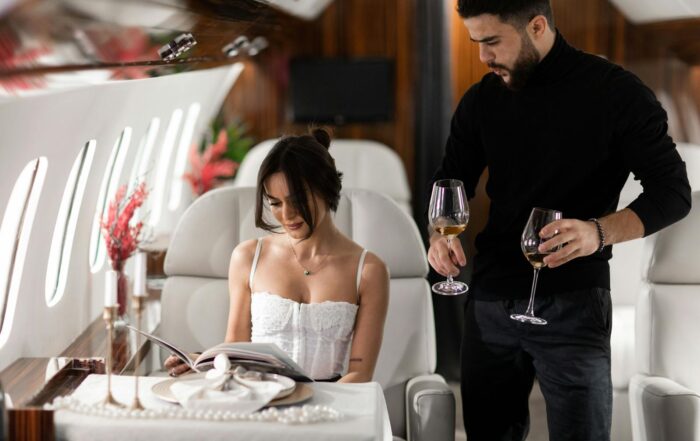 Elegant couple enjoying wine in a luxurious private jet interior.