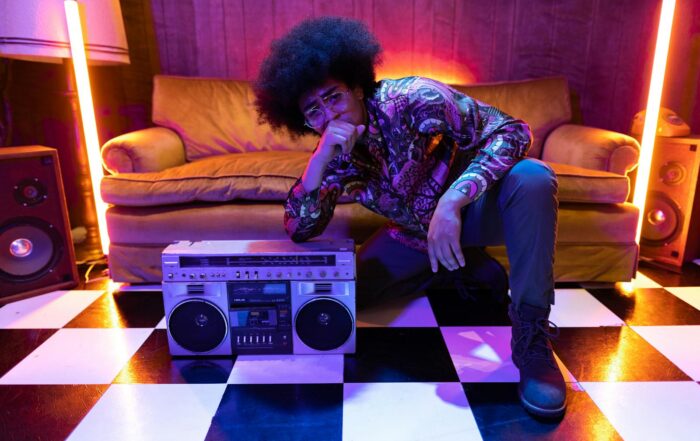 Retro-inspired fashion shoot featuring a person with afro hair posing with a vintage boombox indoors.